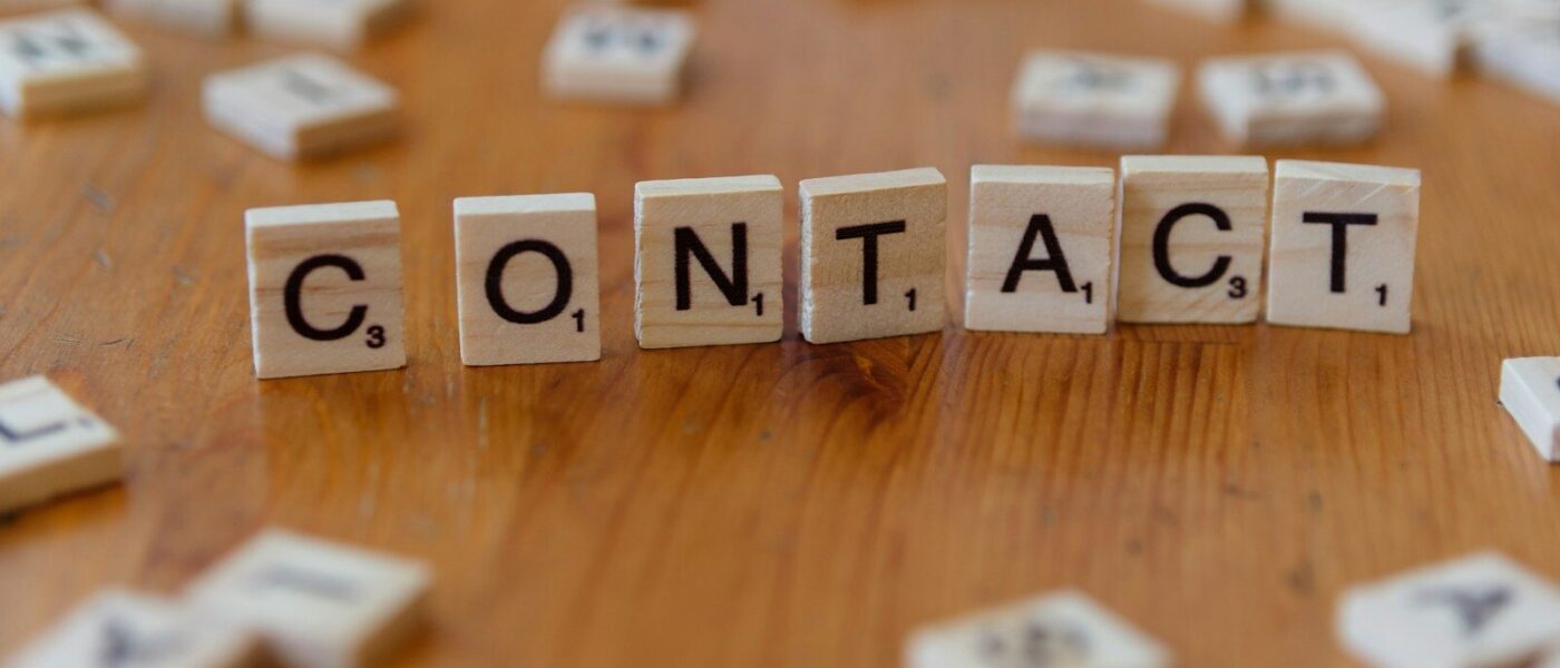A wooden table topped with scrabble tiles spelling contact