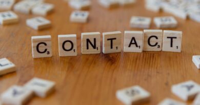 A wooden table topped with scrabble tiles spelling contact