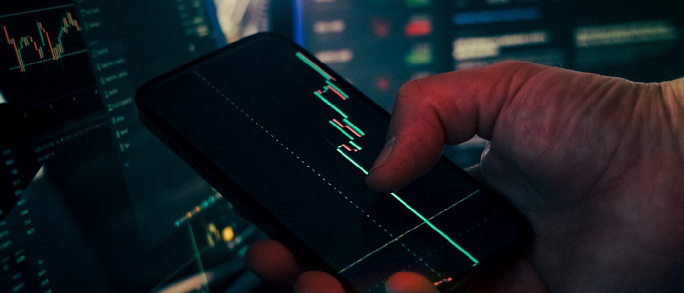 Trader analyzing stock market data on smartphone and phone