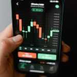 Hand holding smartphone displaying cryptocurrency trading graph in app.