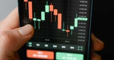 Hand holding smartphone displaying cryptocurrency trading graph in app.