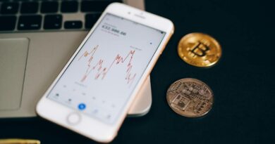 Close-up view of cryptocurrency coins and stock market graph on a smartphone screen.