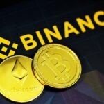 two gold bitcoins sitting next to a binance sign