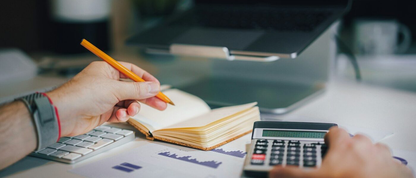 a person sitting at a desk with a calculator and a notebook
