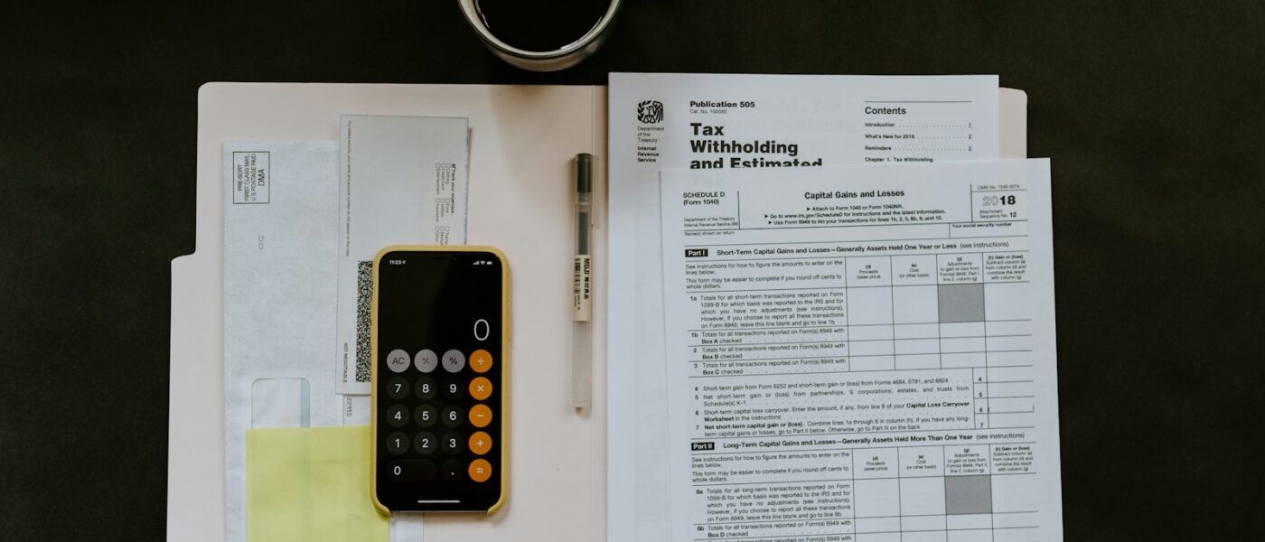 black Android smartphone near ballpoint pen, tax withholding certificate on top of white folder