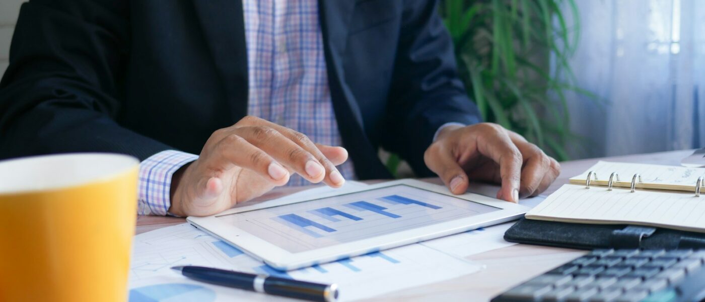 person in black suit jacket holding white tablet computer