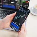 a person holding a cell phone in front of a laptop