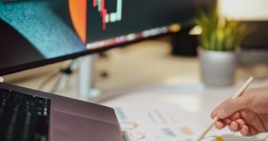 a person writing on a piece of paper next to a computer monitor