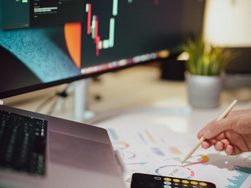 a person writing on a piece of paper next to a computer monitor