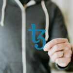 a man in a black hoodie is holding a blue sticker