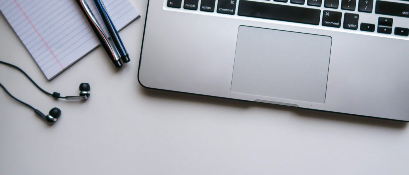 silver laptop computer beside white ruled paper