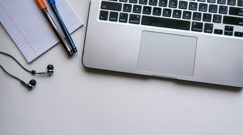silver laptop computer beside white ruled paper