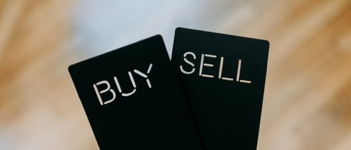 a hand holding two black cards with the words buy and sell written on them